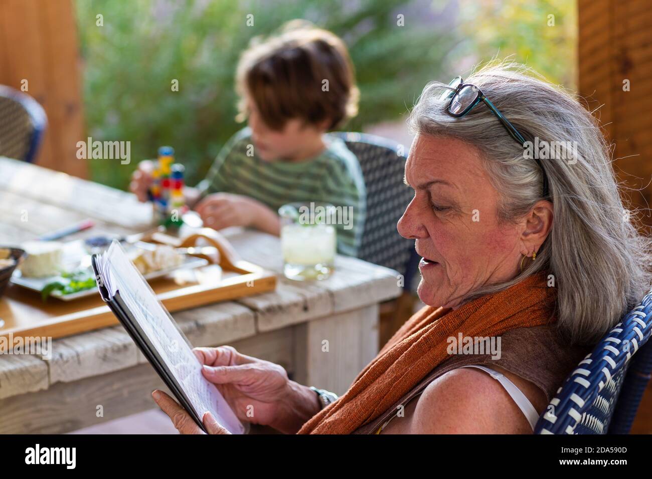Frau liest die Datei draußen auf der Terrasse bei Sonnenuntergang. Stockfoto