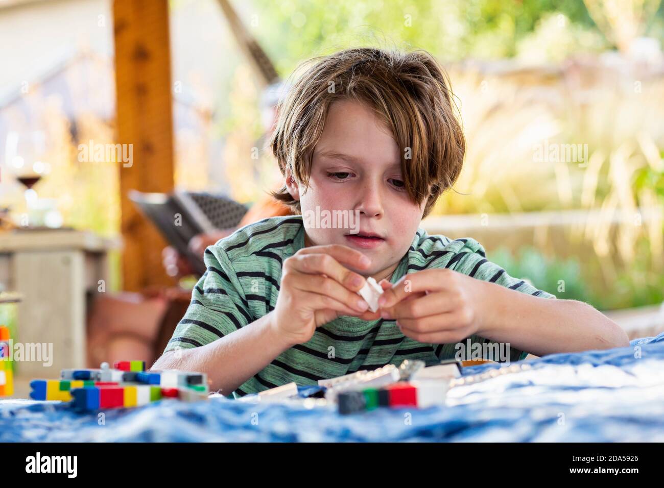 7 Jahre alter Junge, der mit Bausteinen auf einem spielt Terrasse Stockfoto