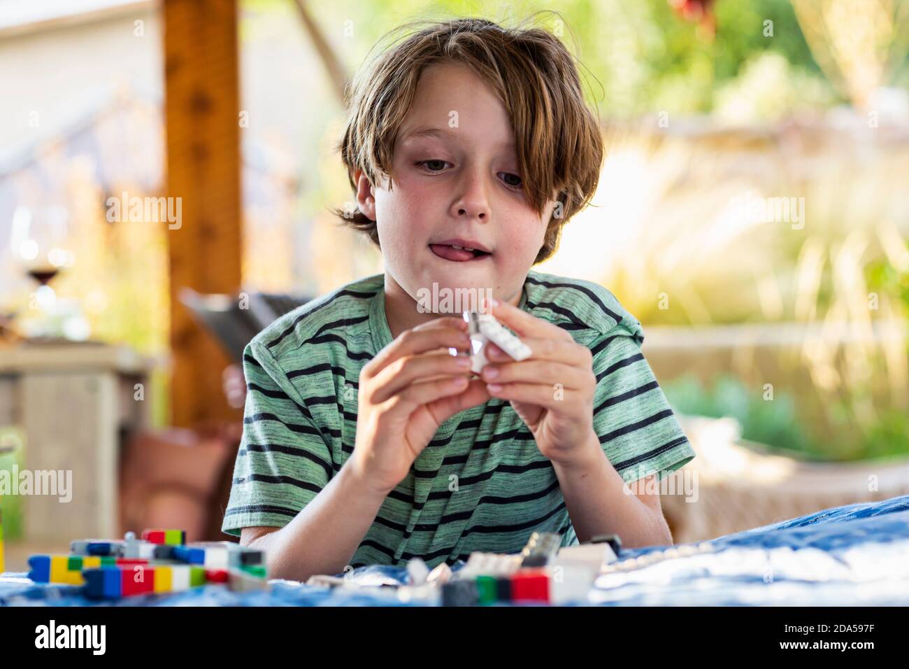7 Jahre alter Junge, der mit Bausteinen auf einem spielt Terrasse Stockfoto