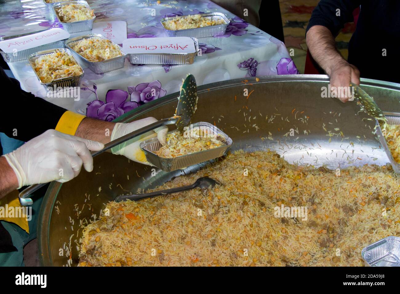 Der Koch stellte gekochten Reis auf Teller. Türkische traditionelle Küche: Pilav. Das Konzept des Humanitarismus. Barda - Aserbaidschan: 10. Oktober 2020 Stockfoto