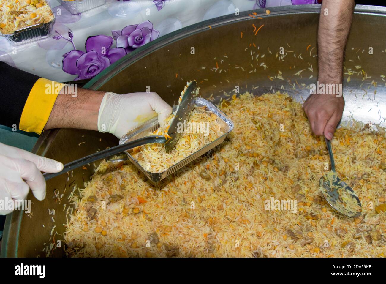 Der Koch stellte gekochten Reis auf Teller. Türkische traditionelle Küche: Pilav. Das Konzept des Humanitarismus. Stockfoto
