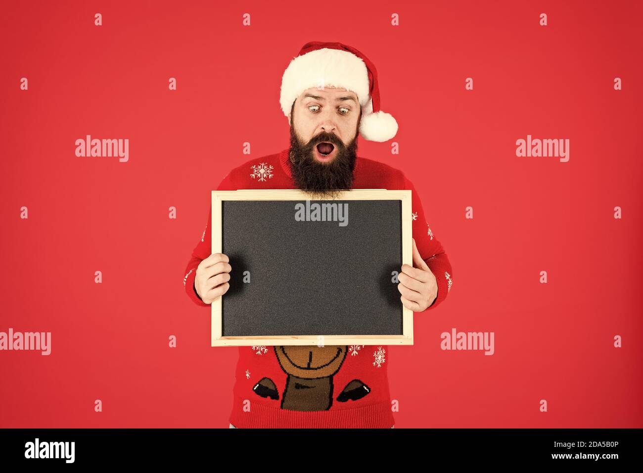 Unglaublich. Winter Ankündigung. Schwarzes Brett für Informationen. Mann leere Tafel kopieren. Guy santa claus roten Hintergrund. Winter event. Winterurlaub. Santa Claus hat mit Werbung. Stockfoto