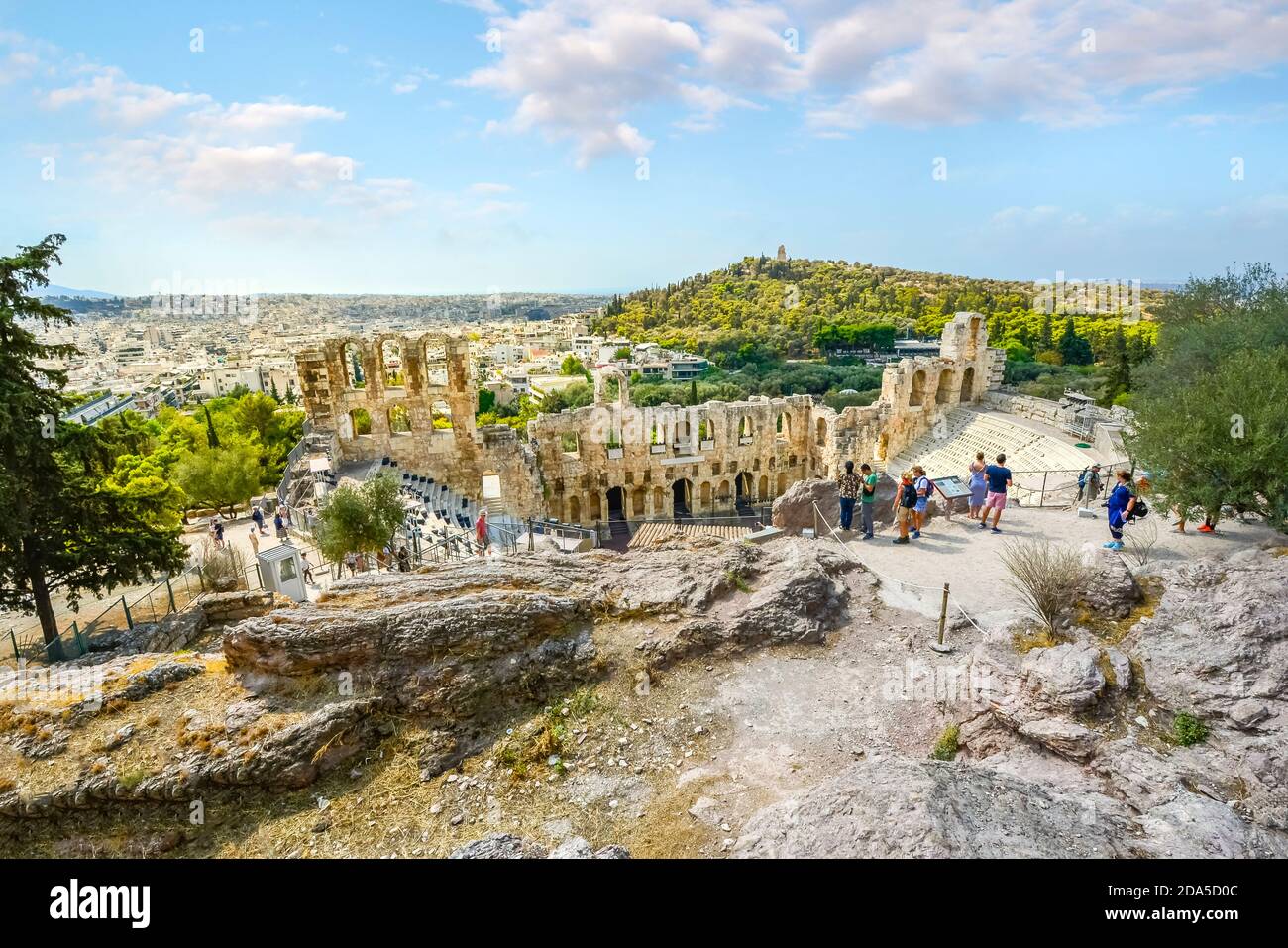Touristen bewundern das Odeon des Herodes Atticus, oder griechisches Theater, auf der Akropolis von Athen Griechenland mit Philopappos Hügel im Hintergrund Stockfoto