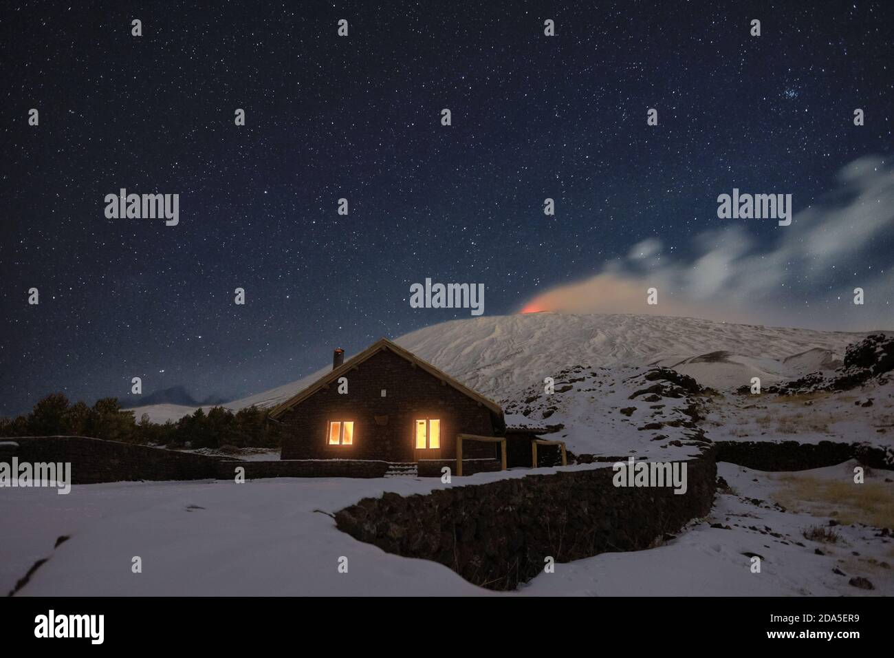 Sternennacht auf Galvarina Refuge mit Fenstern, die unter dem schneebedeckten Vulkan Ätna leuchten, Sizilien Stockfoto