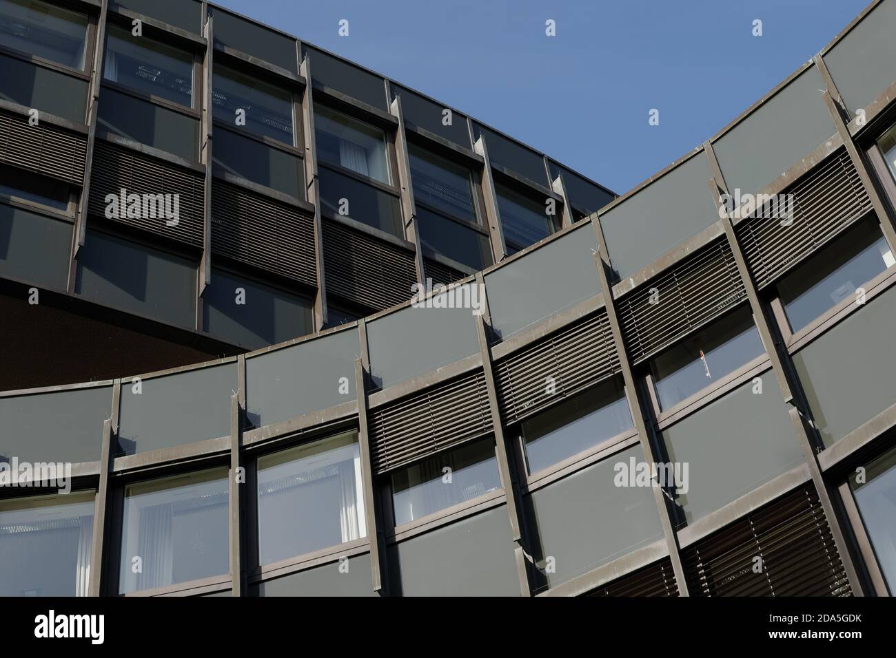 Low-Angle-Ansicht und Nahaufnahme Detail der äußeren Krümmung Fassade mit dunkelgrünen und grauen Aluminium-Verbundplatten in rechteckiger Form. Stockfoto