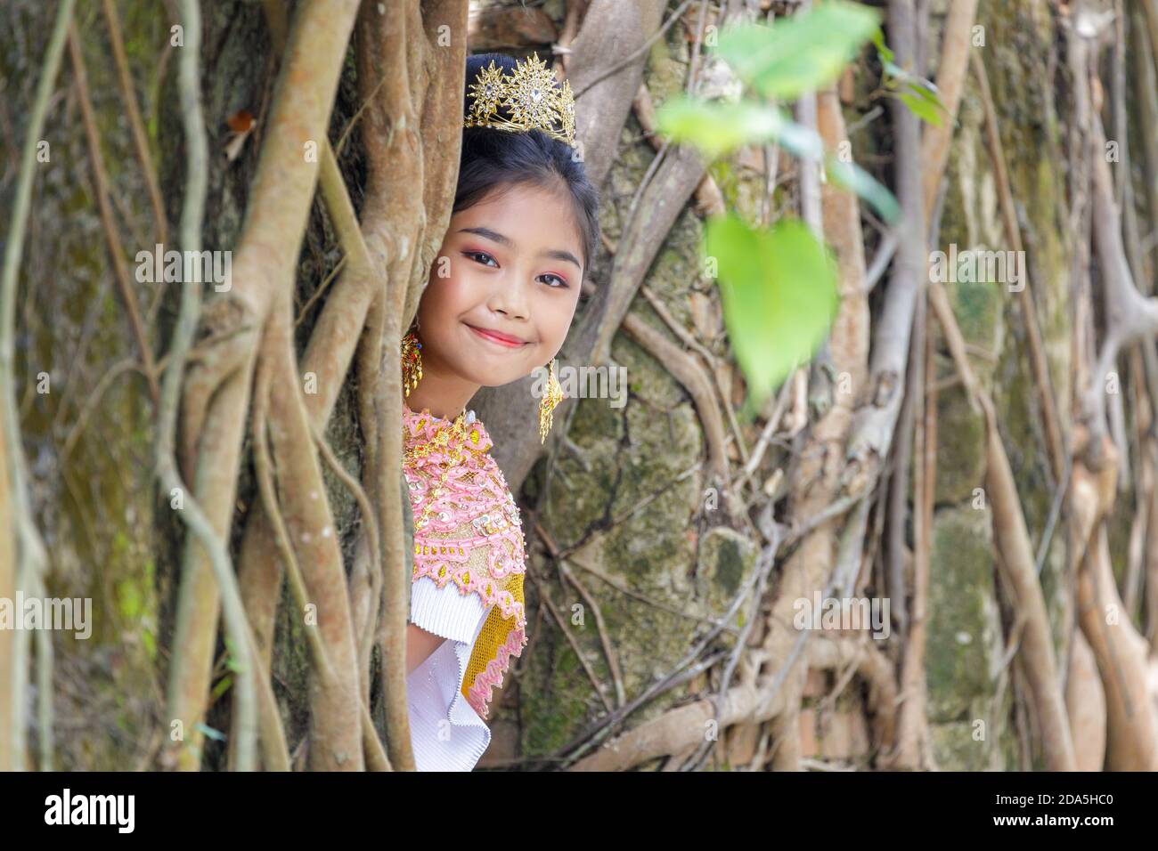 Ein Porträt eines thailändischen Mädchens in einem traditionellen thailändischen Kleid mit einer alten Kirche eines alten thailändischen Tempels. Stockfoto