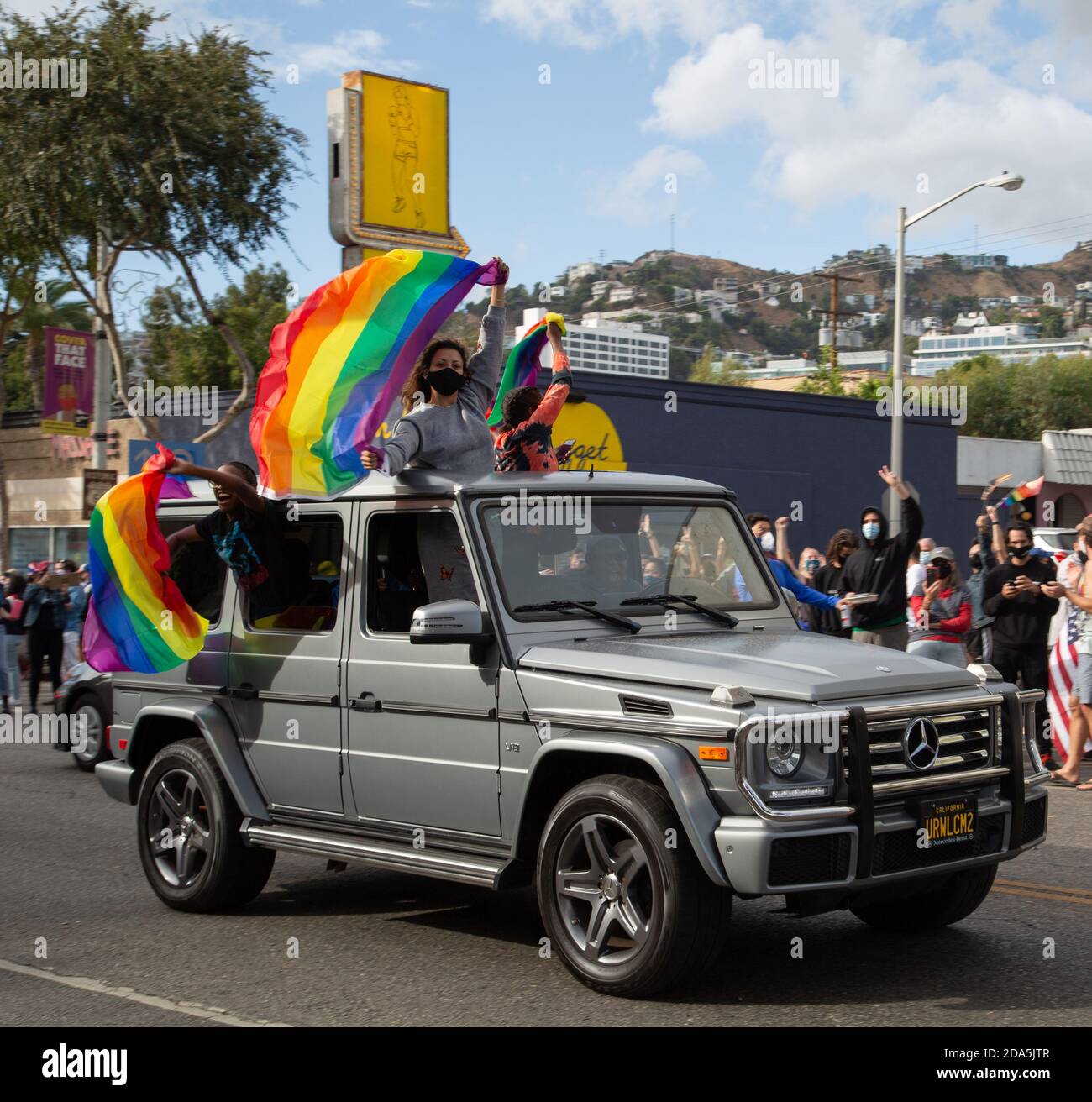 Eine Familie feiert den Sieg von Joe Biden, indem sie während einer improvisierten Parade in West Hollywood, CA, die Regenbogenflagge LGBQT+ aus ihren Autos schwenkt. Stockfoto