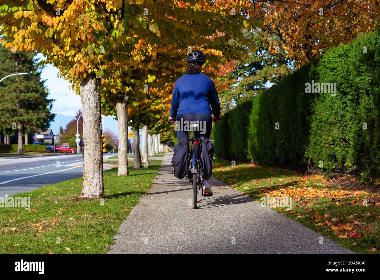 Mädchen, die ein Fahrrad auf einem Bürgersteig in einer ruhigen Nachbarschaft Stockfoto