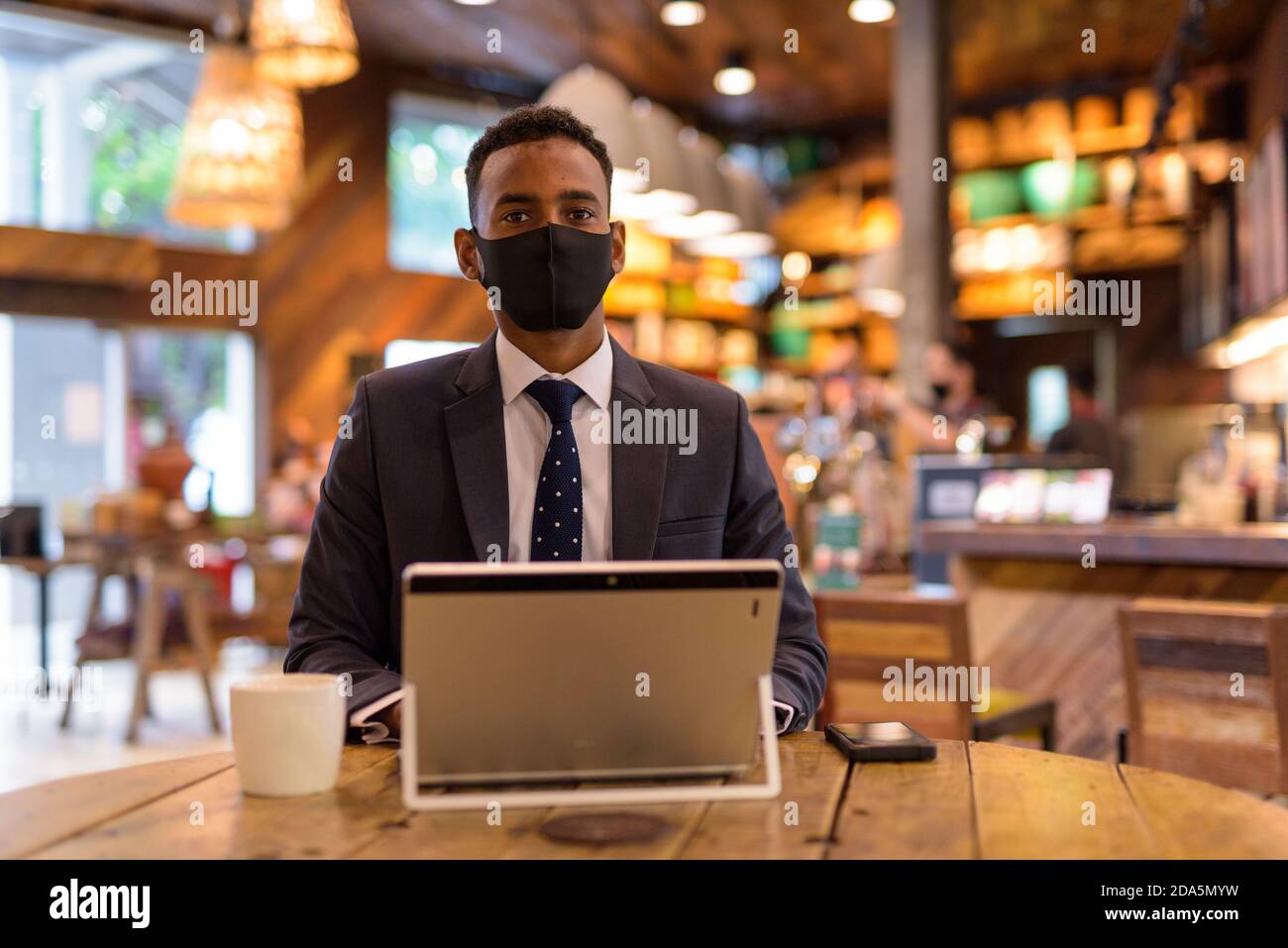 Geschäftsmann mit Laptop, während das Tragen einer schützenden Gesichtsmaske im Kaffee Kaufen Stockfoto