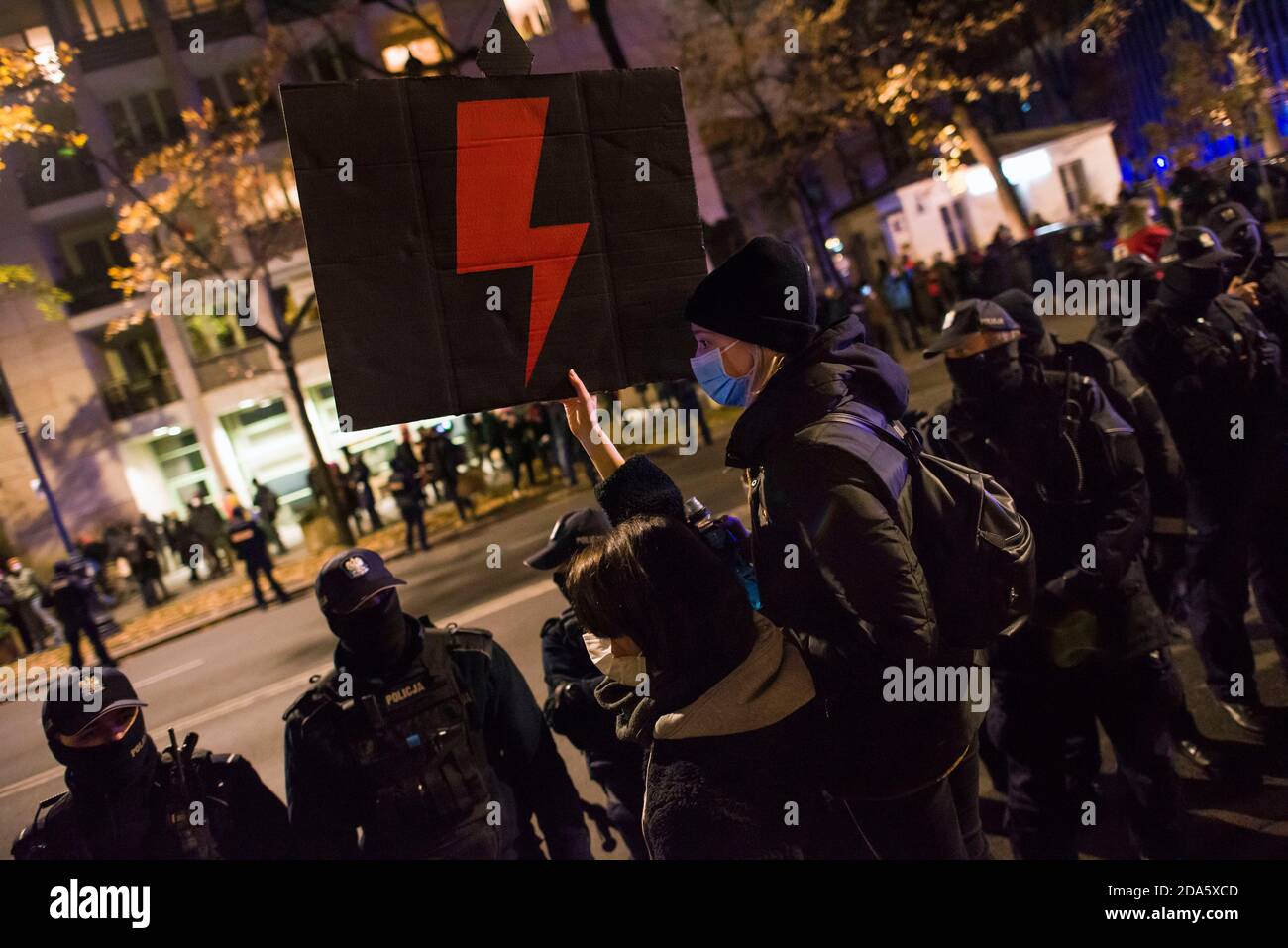 Ein Protestler mit Gesichtsmaske hält ein Plakat mit dem Symbol des Frauenwiderstands, dem roten Blitz während der Demonstration.die Gegner des Urteils des Verfassungsgerichts über Abtreibung protestierten erneut. Hunderte von Menschen versammelten sich vor dem Ministerium für Bildung, um den Rücktritt des Ministers für Bildung und Wissenschaft, Przemyslaw Czarnek, zu fordern, der für seine homophoben und chauvinistischen öffentlichen Äußerungen bekannt ist. Bei mehreren Gelegenheiten zerstreute die Polizei gewaltsam Demonstranten, die versucht hatten, den Verkehr zu blockieren und unerwartet durch das Stadtzentrum marschierten. Zahlreich Stockfoto
