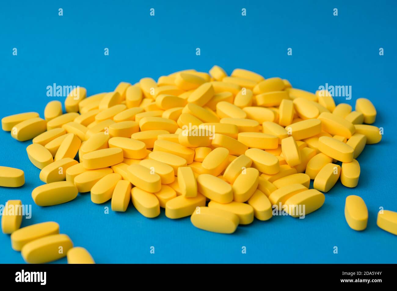 Pharmazie Industrie Konzept viele gelbe Pillen Tabletten auf blauem Hintergrund Stockfoto