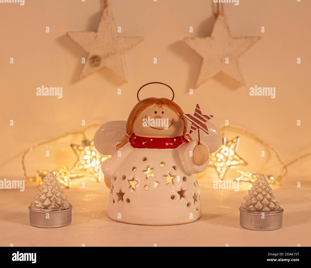 weihnachtliche festliche Kulisse mit einem Engel Ornament in warmem goldenem Licht; Vorderansicht mit verschwommenem Bokeh-Sternenlicht Hintergrund auf weißem Holztisch Stockfoto