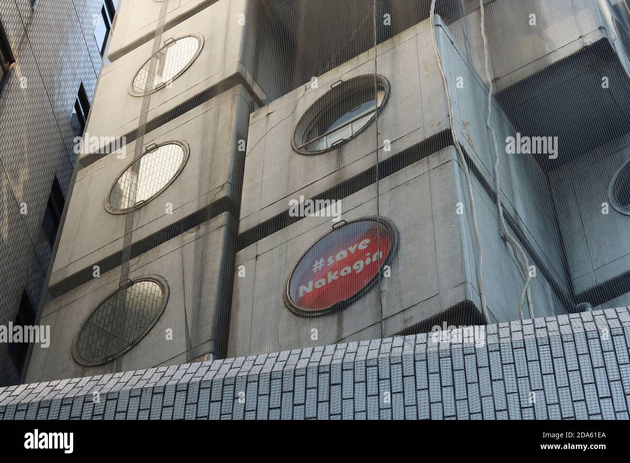 Nahaufnahme des legendären Nakagin Capsule Tower in Tokio von Kisho Kurokawa. Ein Zeichen in einem Fenster lautet '#Save Nagakin'. (Oktober 2020) Stockfoto