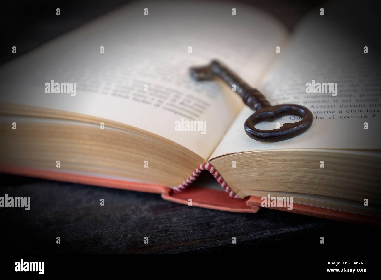 Ein alter Schlüssel lehnt sich in einem alten Buch gegen Schwarzer Hintergrund Stockfoto