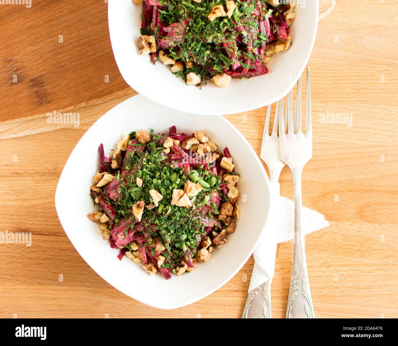 Salat mit gekochten Rüben und Walnüssen, verziert mit Kräutern. Blick von oben. Schöne Präsentation des Gerichts. Stockfoto