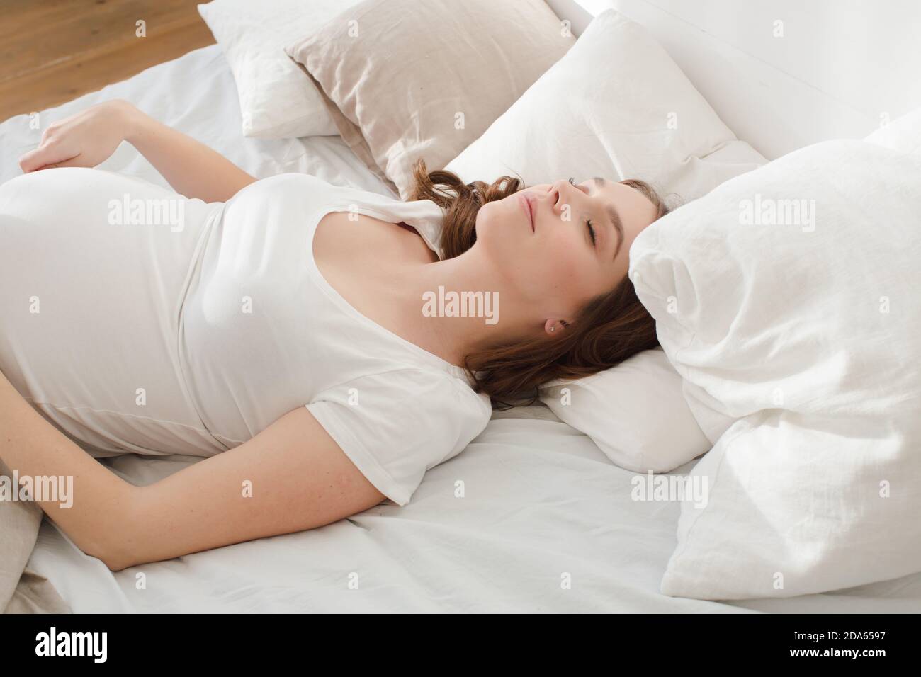 Schwanger, lächelnde Frau auf Bett liegend Stockfoto