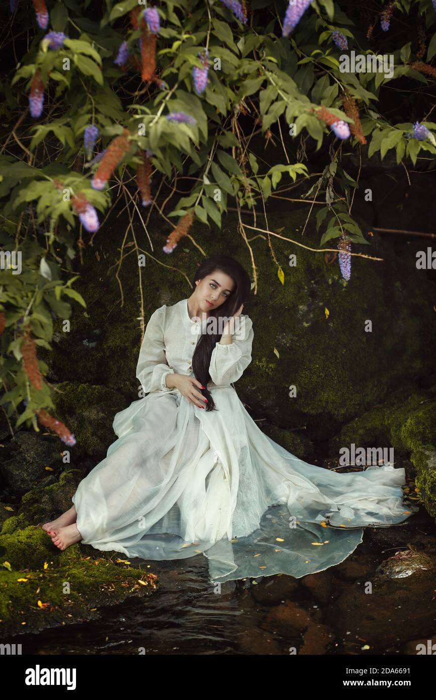 Romantische Frau zwischen den Blumen des Waldes Stockfoto