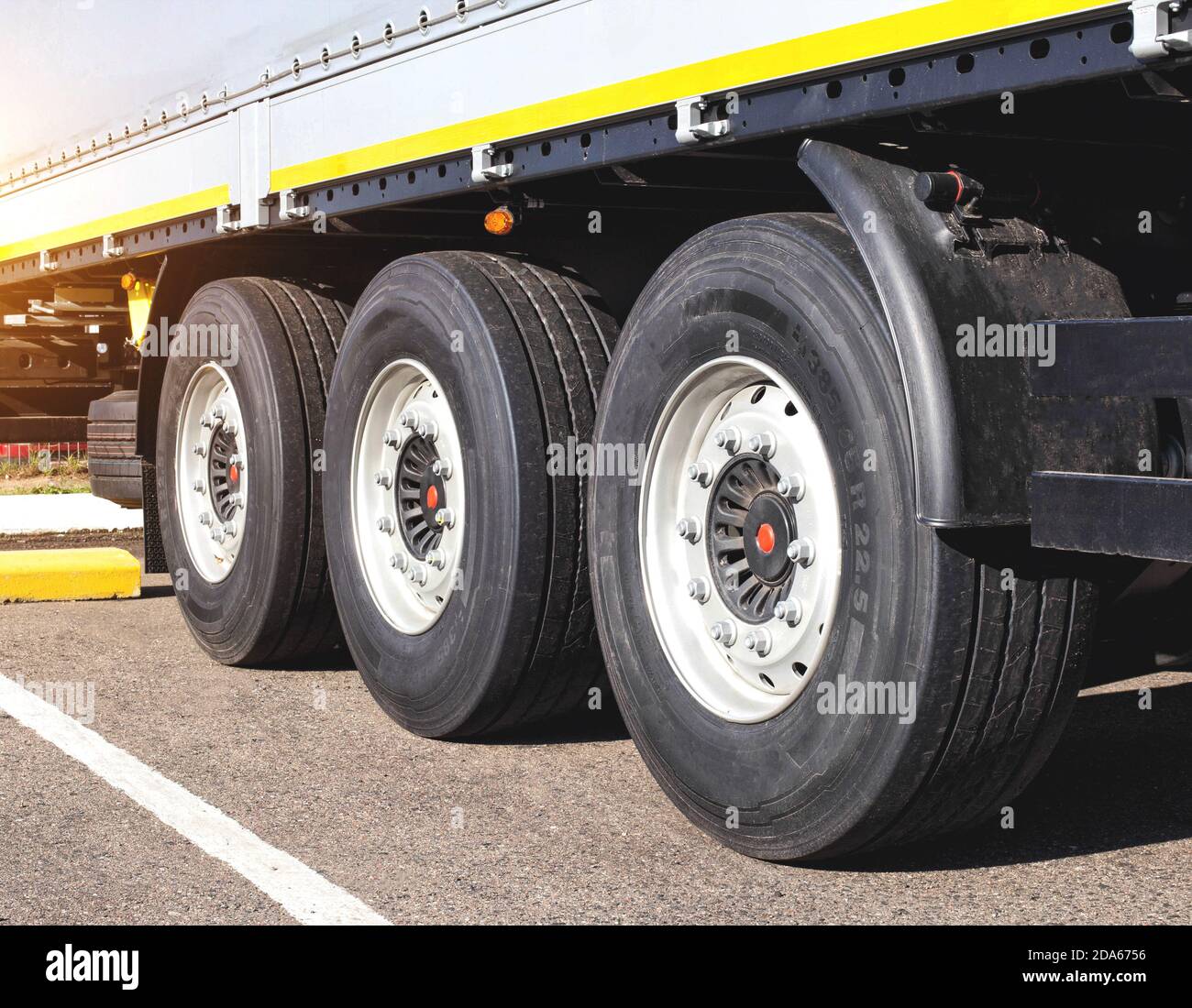 Räder mit Gummi auf der Ladung 3-Achsen-Anhänger des Traktors. Das Konzept der Wahl von hochwertigem Gummi für den Straßenverkehr. Kraftstoffverbrauch und Straßen Stockfoto
