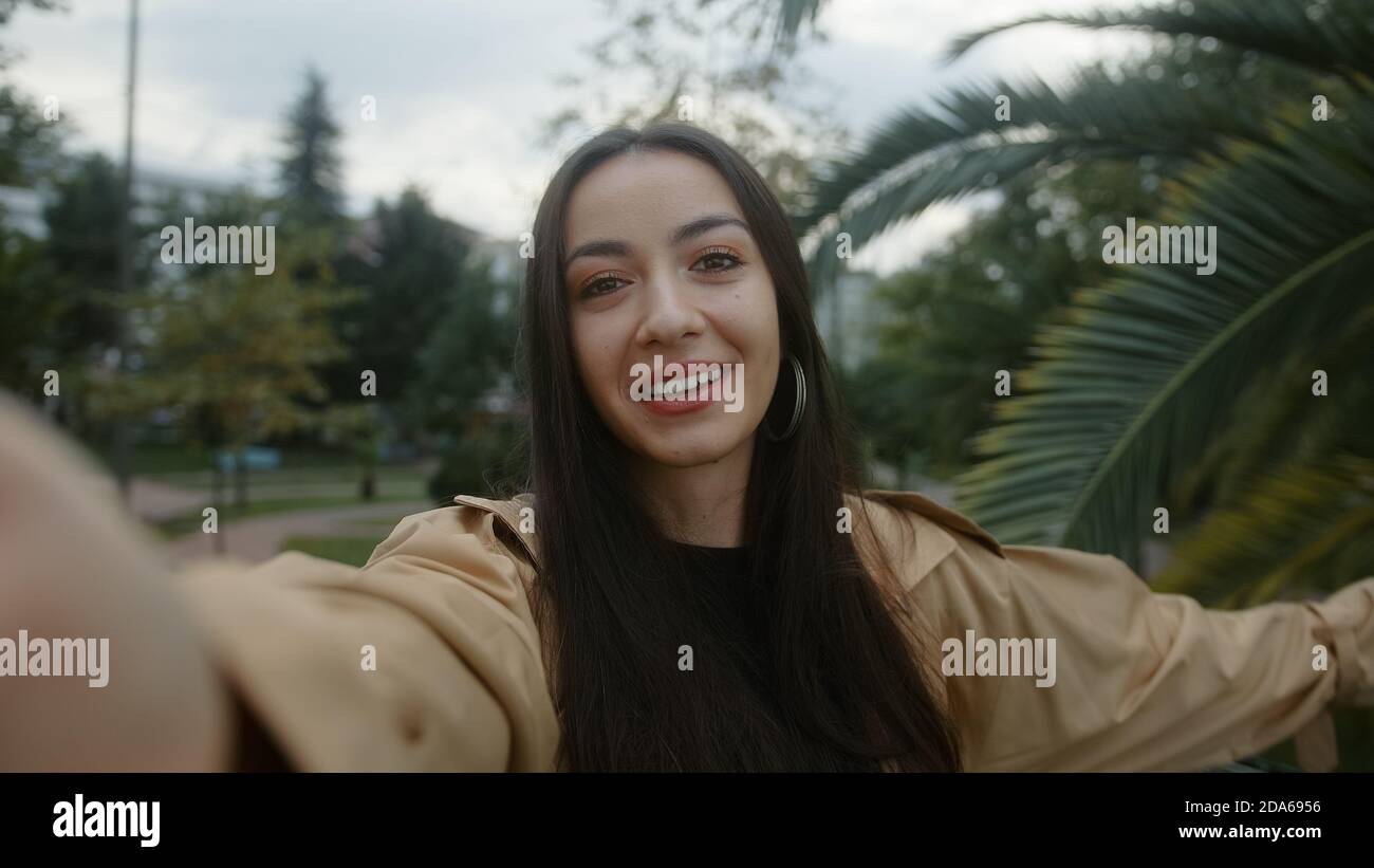 Schöne junge lächelnde Gesicht Frau hält Kamera oder Telefon in der Hand und sie macht Videoanruf oder sie ist die Aufnahme von Video für ihre Fans, sie ist überrascht Stockfoto