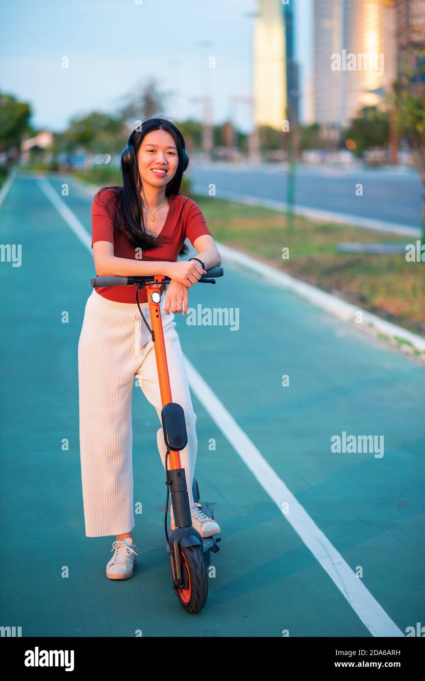 Frau mit Elektroroller für den Transport in einer modernen Stadt Umgebung Stockfoto