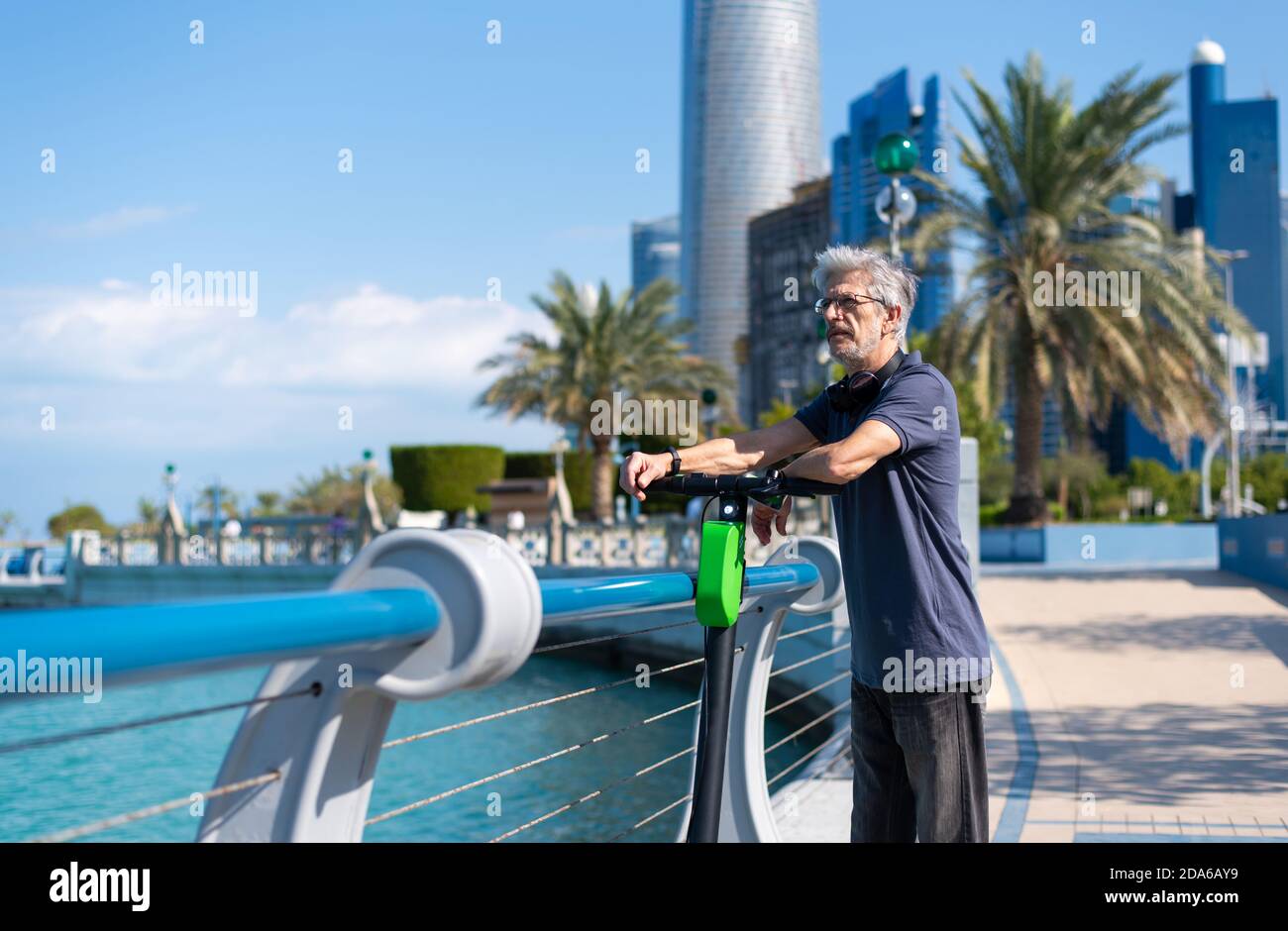 Älterer Mann, der sich ausruhte, während er eine Fahrt mit dem Elektroantrieb hatte Roller für den Transport in einer modernen Stadtumgebung Stockfoto
