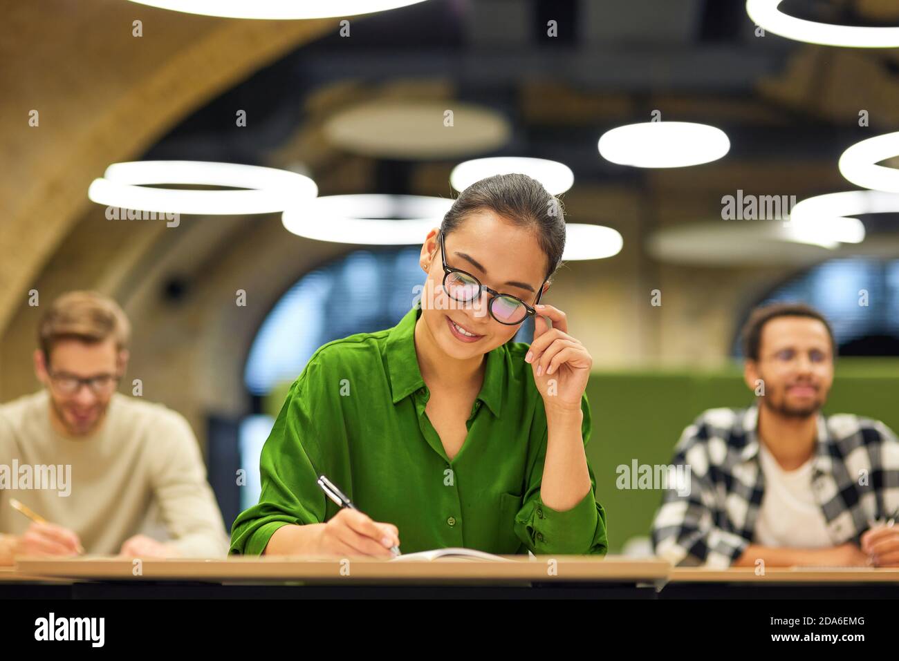 Nie aufhören zu lernen. Fokussierte asiatische Frau tragen Brillen machen einige Notizen während des Studiums mit Kollegen während Corporate Training oder Seminar. Business Education Konzept Stockfoto