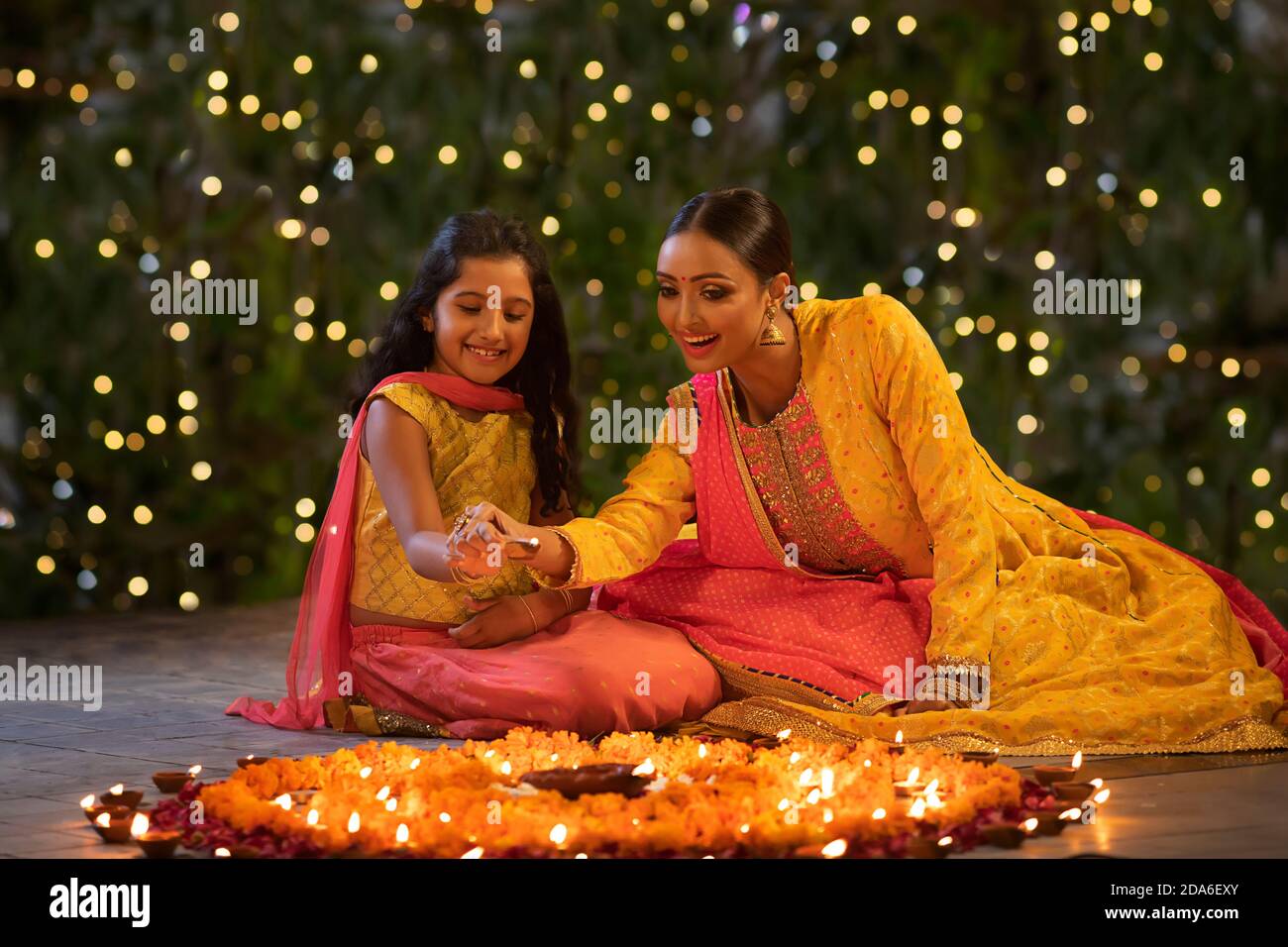 Mutter und Tochter setzen Diyas zusammen Stockfoto