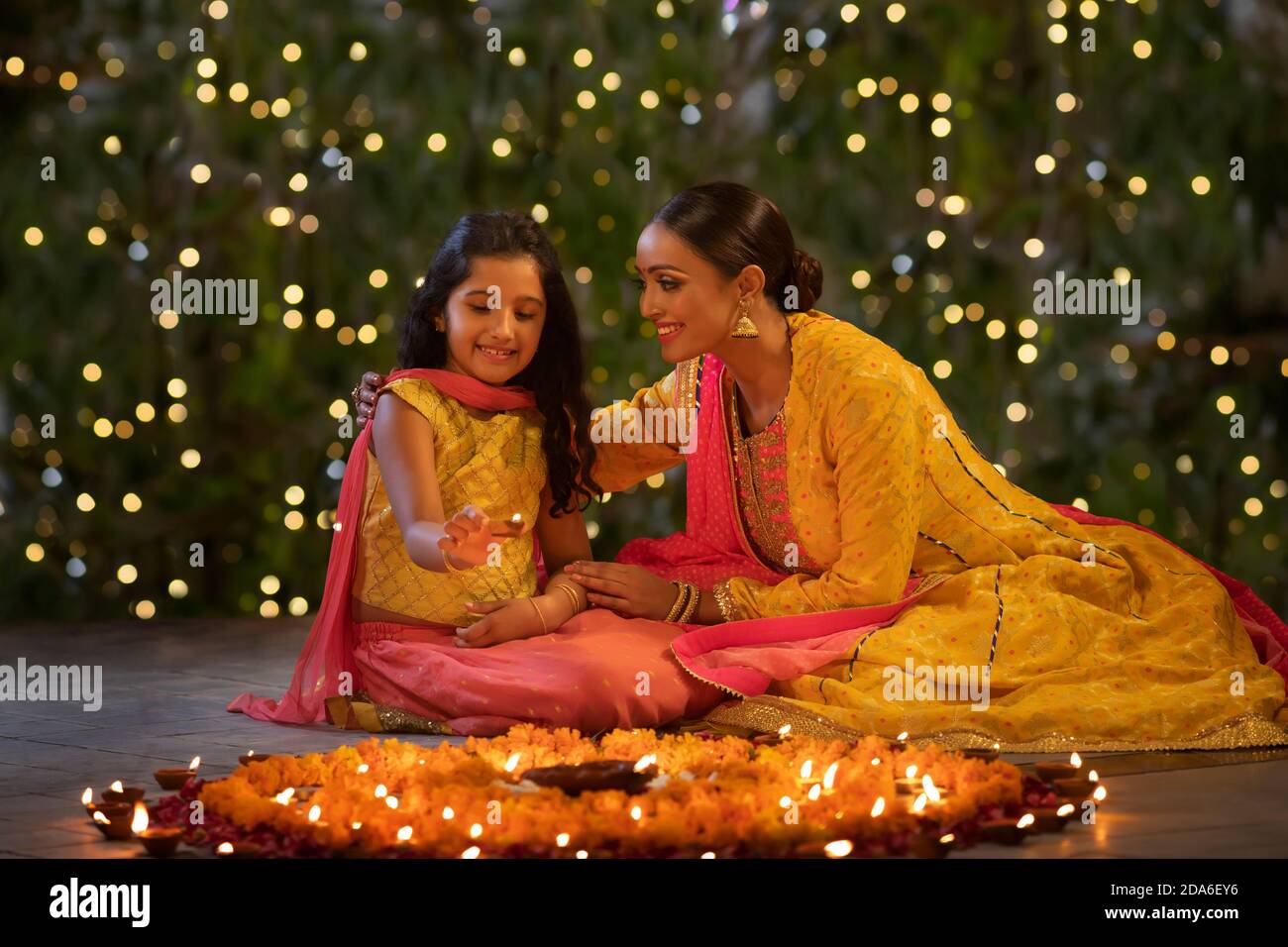 Mutter und Tochter setzen Diyas zusammen Stockfoto