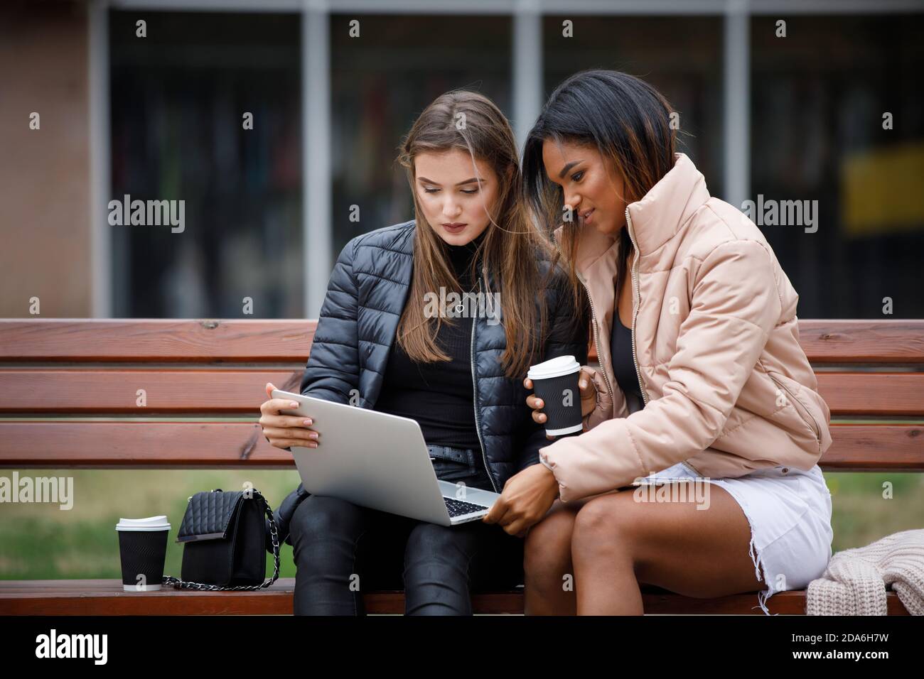 Zwei Studenten Mädchen sitzen mit Laptop auf der Bank Stockfoto