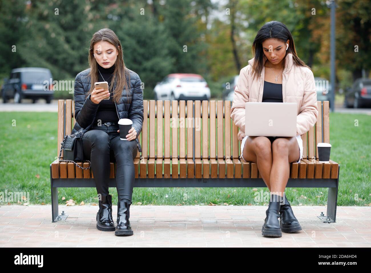 Zwei verschiedene Frauen sitzen auf der Bank im Park Stockfoto
