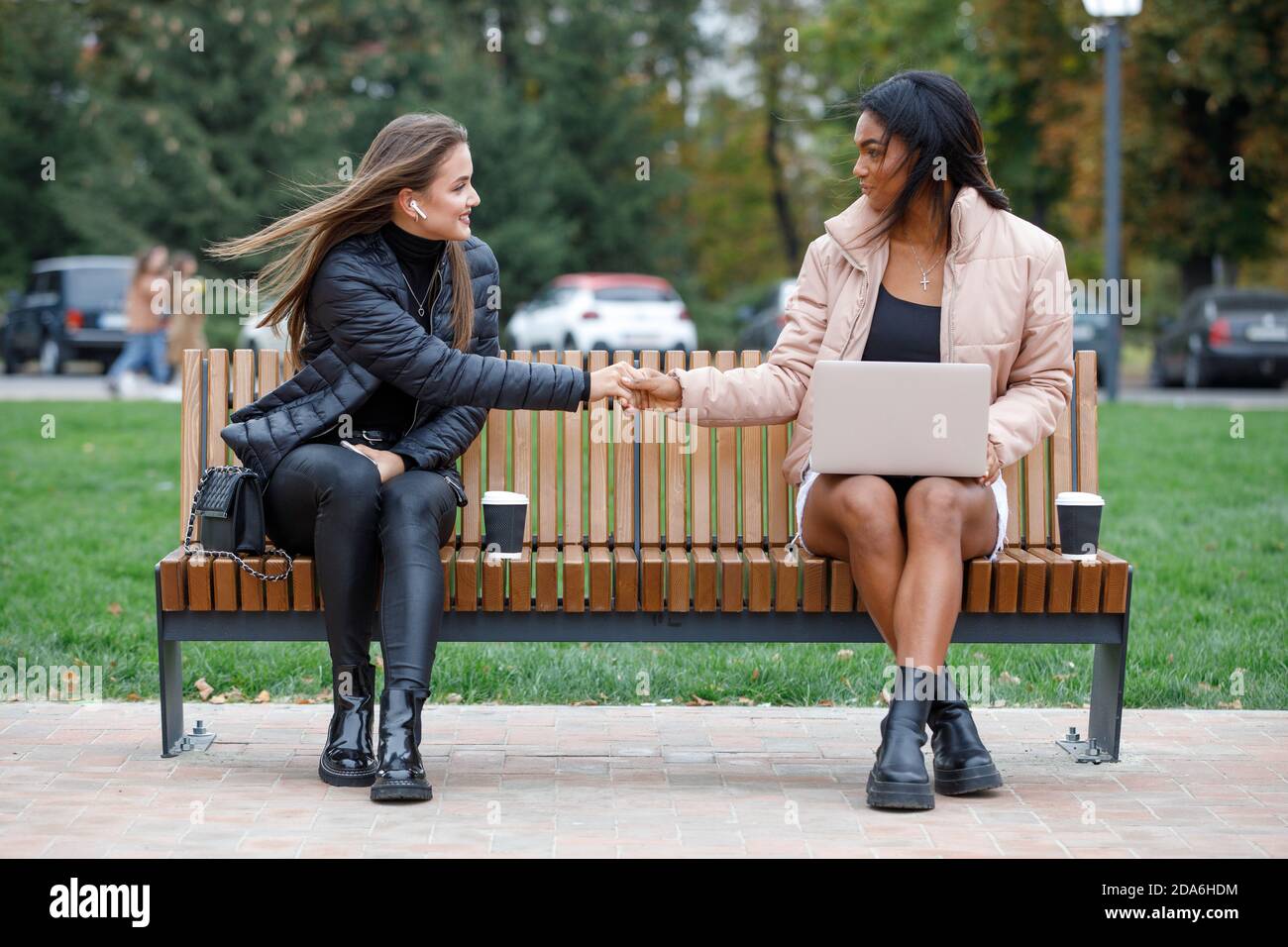 Zwei Frauen plaudern auf der Bank mit sozialer Distanzierung Stockfoto