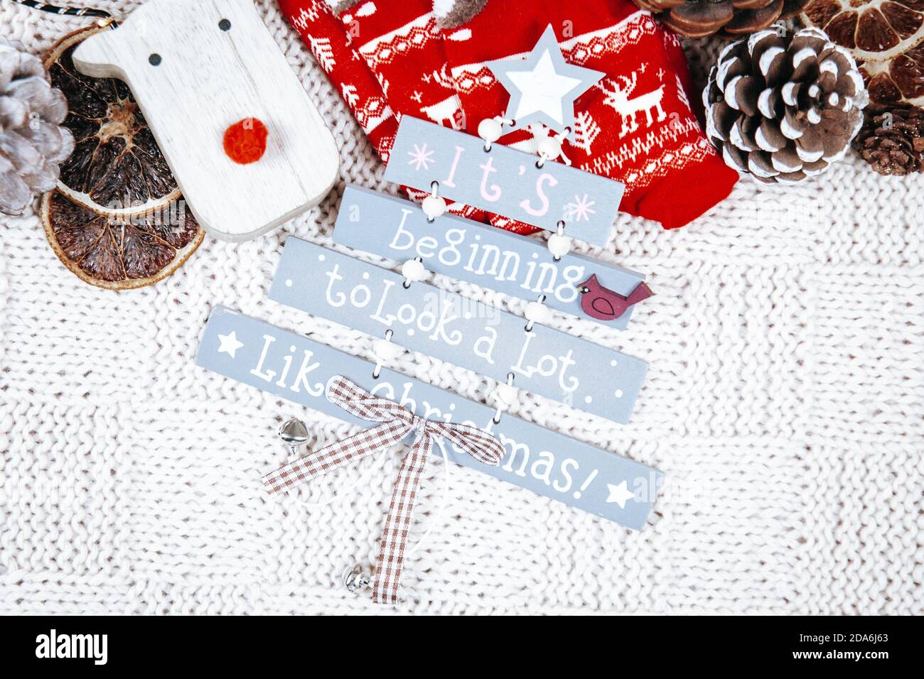 Es fängt an, viel wie Weihnachtsschild mit Weihnachtsdekorationen auf einer weißen Strickdecke aussehen. Weihnachtsstimmung. Stockfoto