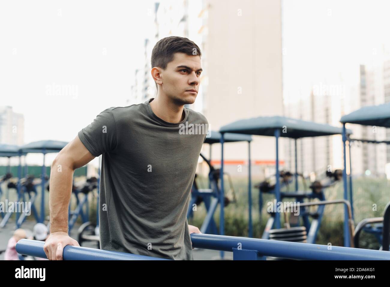 Starker muskulöser junger Mann arbeitet im Fitnessstudio im Freien. Nahaufnahme eines jungen starken Teenagers, der an der horizontalen Stange Pull-up macht. Stockfoto