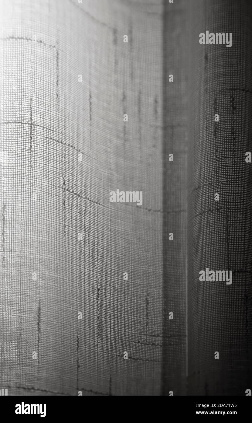 Licht kommt durch einen durchsichtigen Vorhang aus Baumwollspitze. Abstrakter Vollformat-Hintergrund in Schwarz und Weiß. Stockfoto