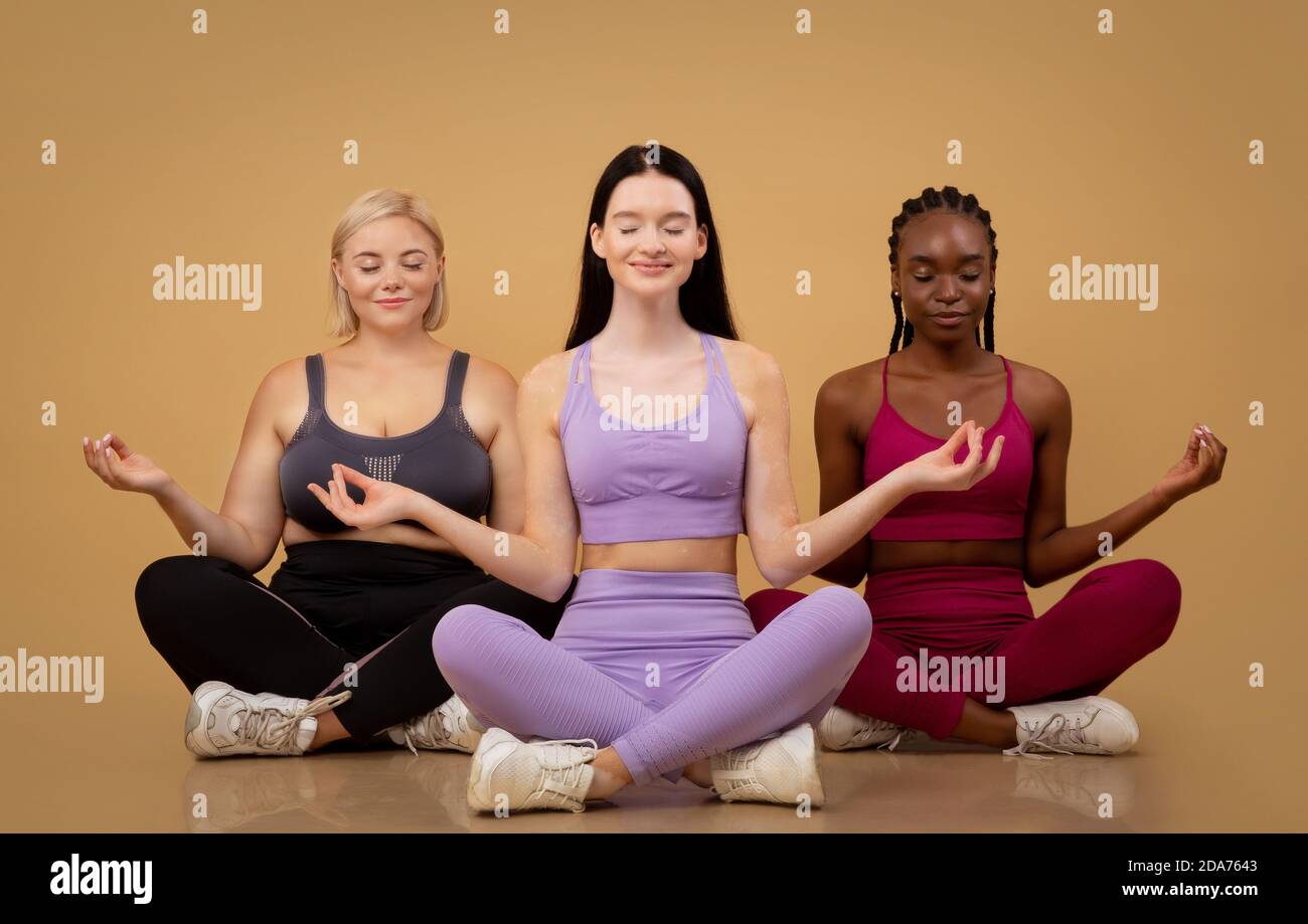 Schöne Körper positive Frauen unterschiedlicher Größe und Erscheinungen meditieren Gemeinsam in Innenräumen Stockfoto