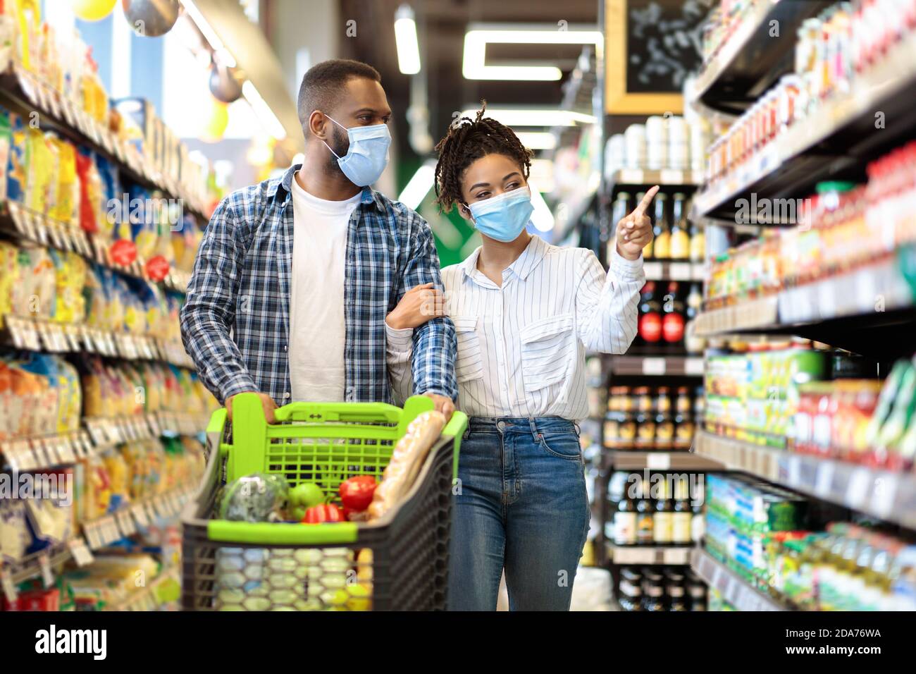 Afrikanisches Paar In Schutzmasken Im Supermarkt Tun Lebensmittelgeschäft Einkaufen Stockfoto