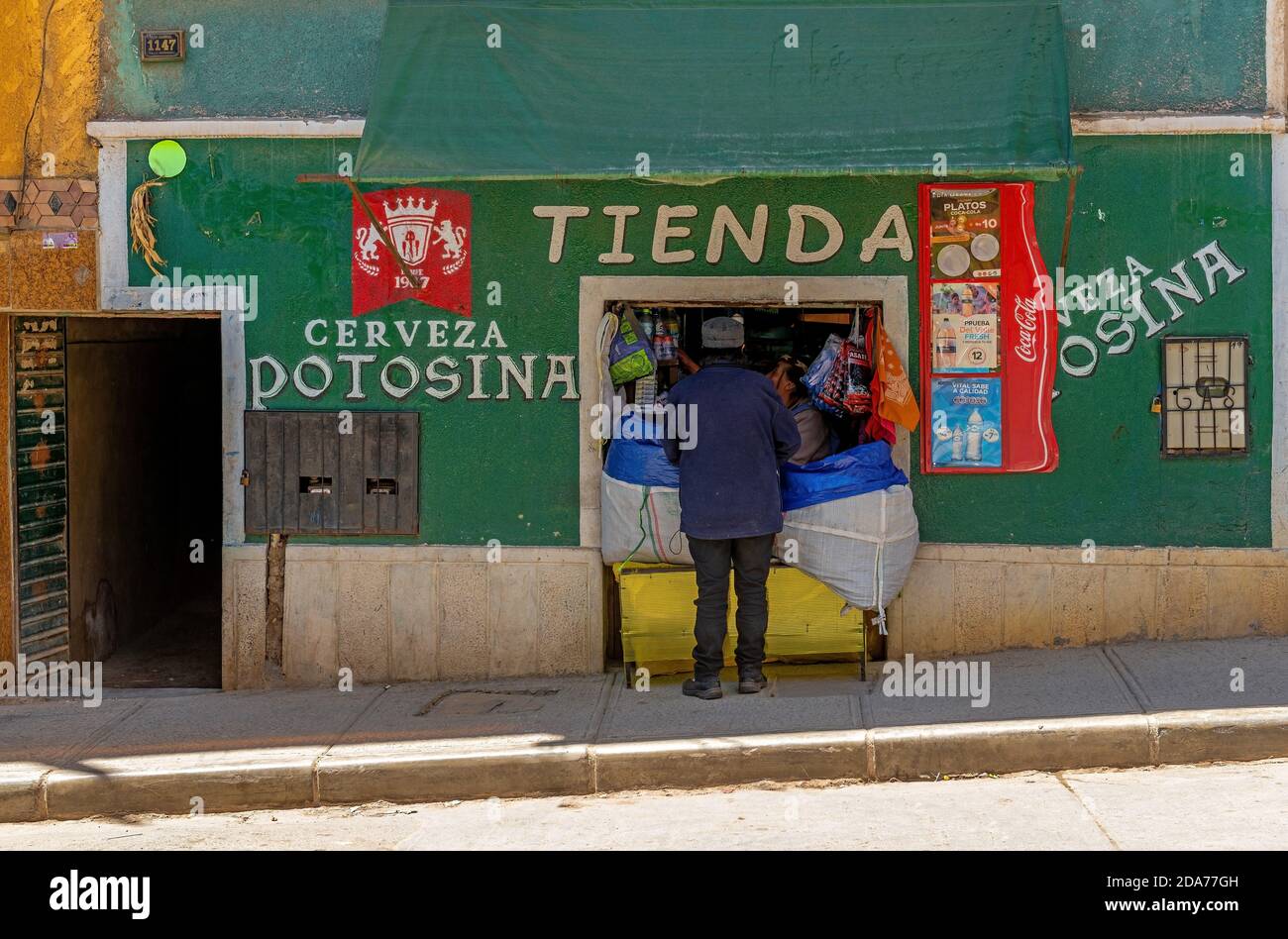 Mann einkaufen in der Stadt Potosi mit einer Ladenfassade mit Zeichen von Potosina Bier, Bolivien. Stockfoto