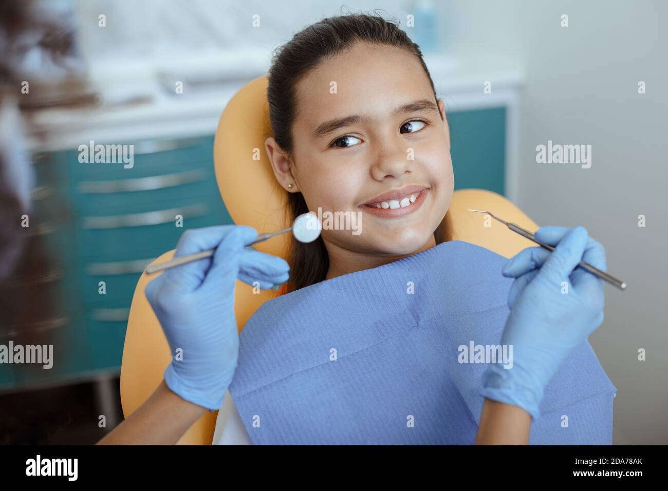 afroamerikanischer Arzt in Gummihandschuhe mit Stomatologie Werkzeug für Behandelt Zahn des lächelnden kleinen Kindes Stockfoto