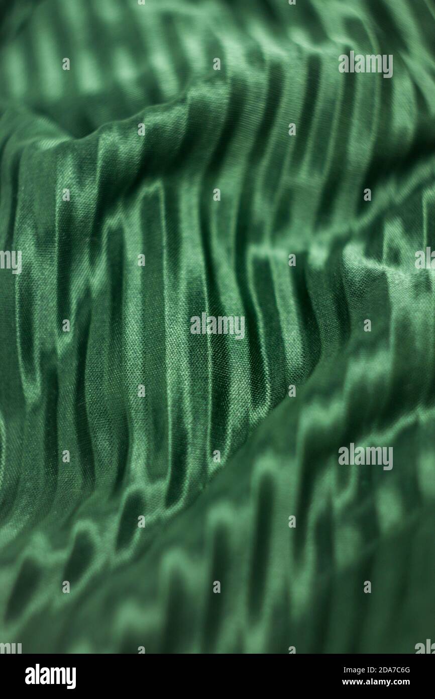 Textur, Hintergrund, Muster, Seidenstoff in grüner Farbe. Grüne Seide. Faltenstoff. Stockfoto