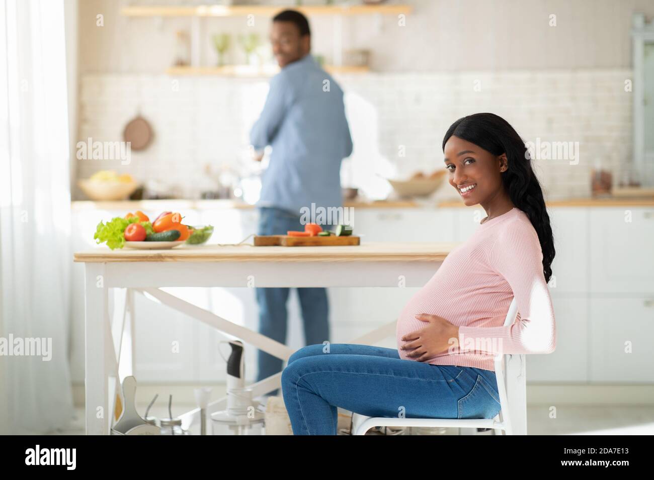 Gesunde Ernährung während der Schwangerschaft. Schöne erwartungsvolle Frau wartet auf ihren Mann gesundes Frühstück in der Küche zu kochen Stockfoto