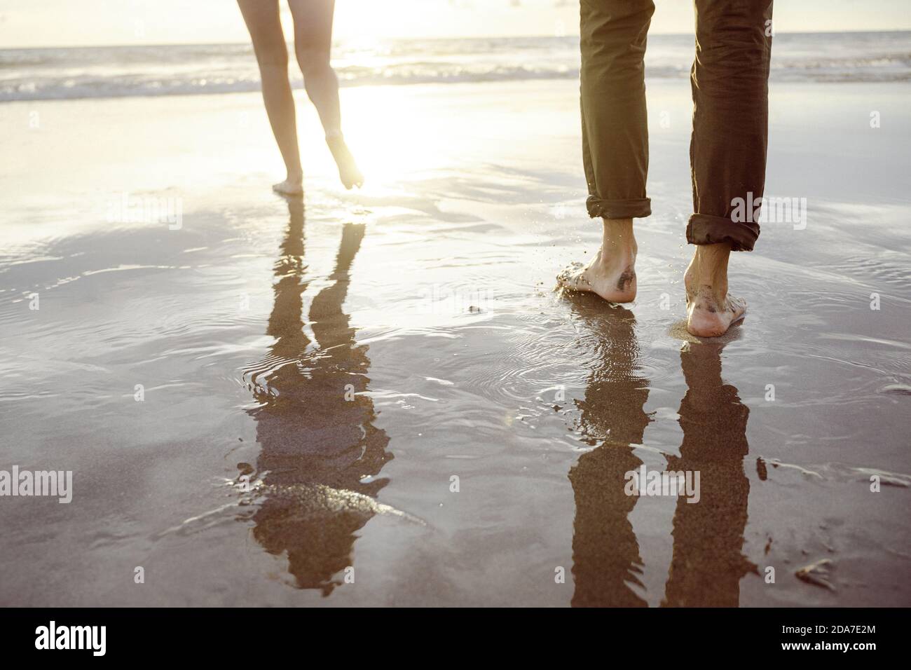 Männerfüße mit nasser Hose und eine Frau, die weit läuft Weg Stockfoto