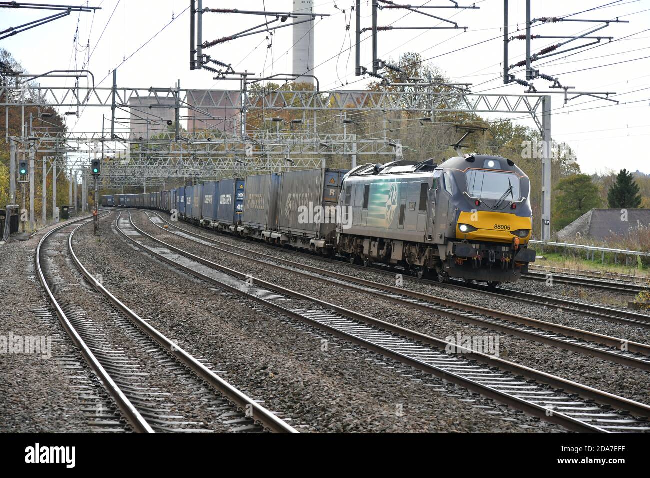 Direct Rail Services Elektro-Diesel Klasse 88 88005 lehnt sich an Kurven durch Rugeley Trent Valley mit einem voll beladenen Tesco Containerzug Stockfoto