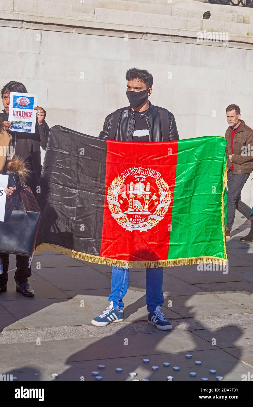 Eine Versammlung von Aktivisten für Frieden in Afghanistan, die ihre Botschaft auf den Londoner Trafalgar Square bringen. Ein junger Mann pariert die afghanische Flagge. Stockfoto