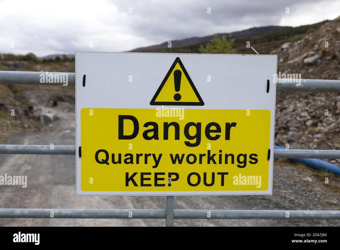 Schild „Danger Quarry Abbaustätten halten sich aus“ an einem verzinkten Metalltor am Eingang zu einem Steinbruch, Schottland. Stockfoto
