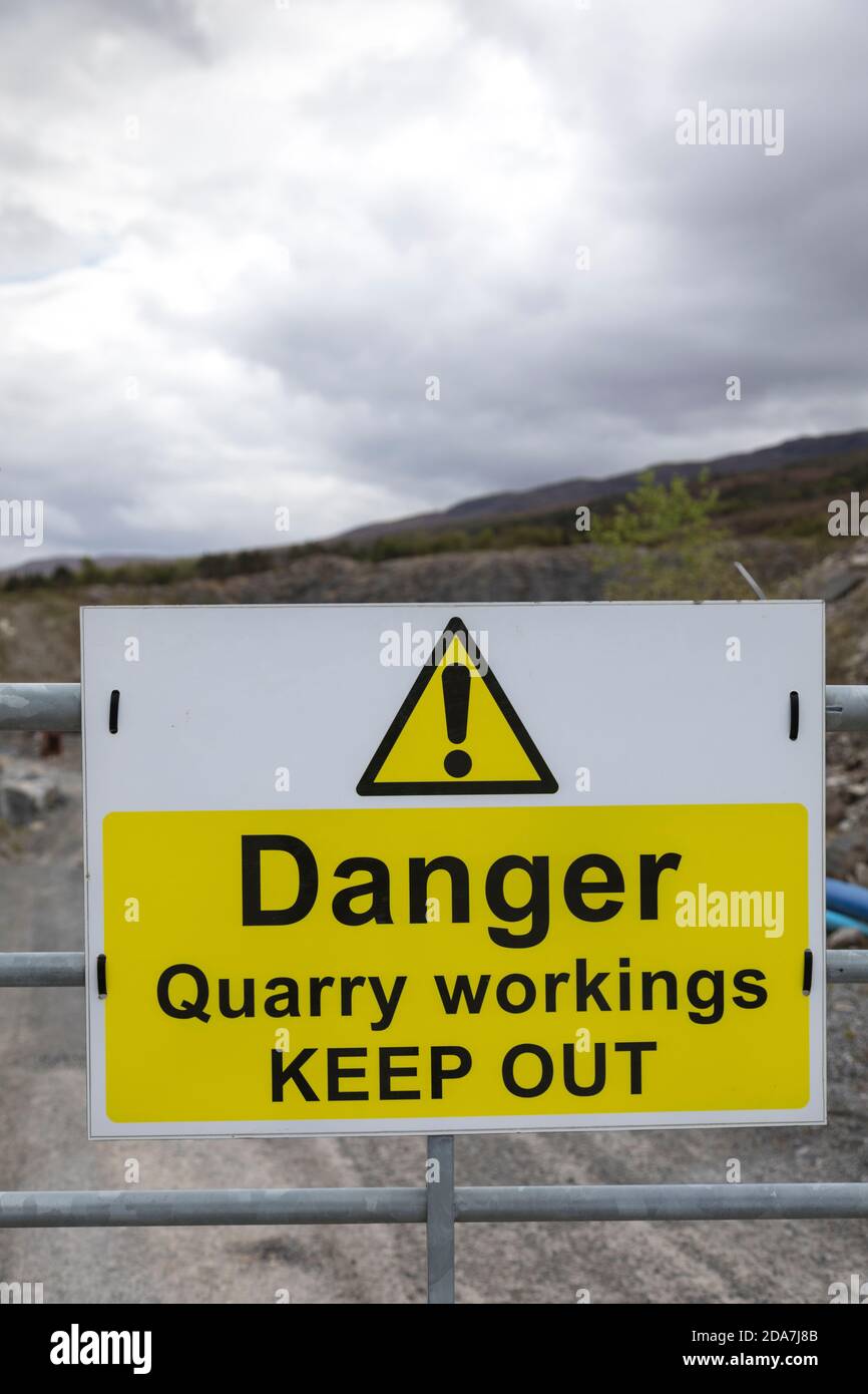 Schild „Danger Quarry Abbaustätten halten sich aus“ an einem verzinkten Metalltor am Eingang zu einem Steinbruch, Schottland. Stockfoto