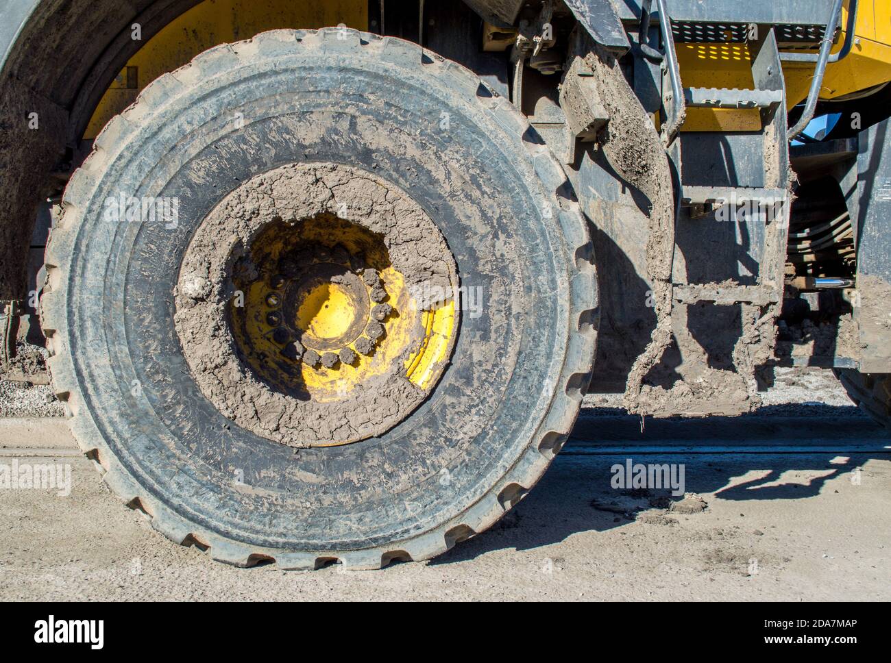Nahaufnahme eines großen schweren Schlamm gekackten Bulldozer Reifen und Metalltreppen zur Kabine Stockfoto
