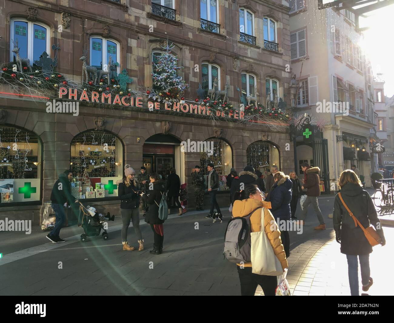 Straßburg, Frankreich - 3. Dezember 2016: Große Gruppe von Fußgängern und schöne Sonneneinstrahlung auf dem zentralen Platz Homme de Fer und Apotheke Drogerie mit dem gleichen Namen Stockfoto