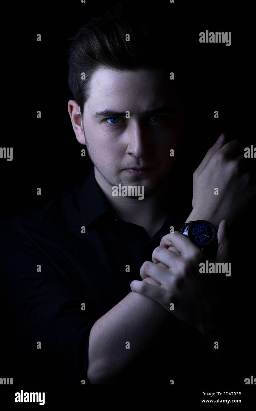 Mann in schwarzem Hemd, der die Kamera mit dem Arm anschaut. Stockfoto