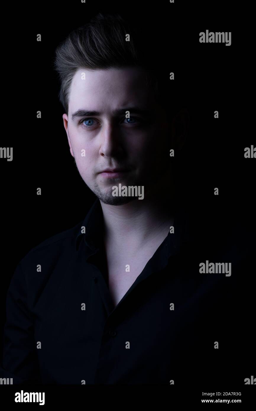 Mann in schwarzem Hemd, der die Kamera mit dem Arm anschaut. Stockfoto