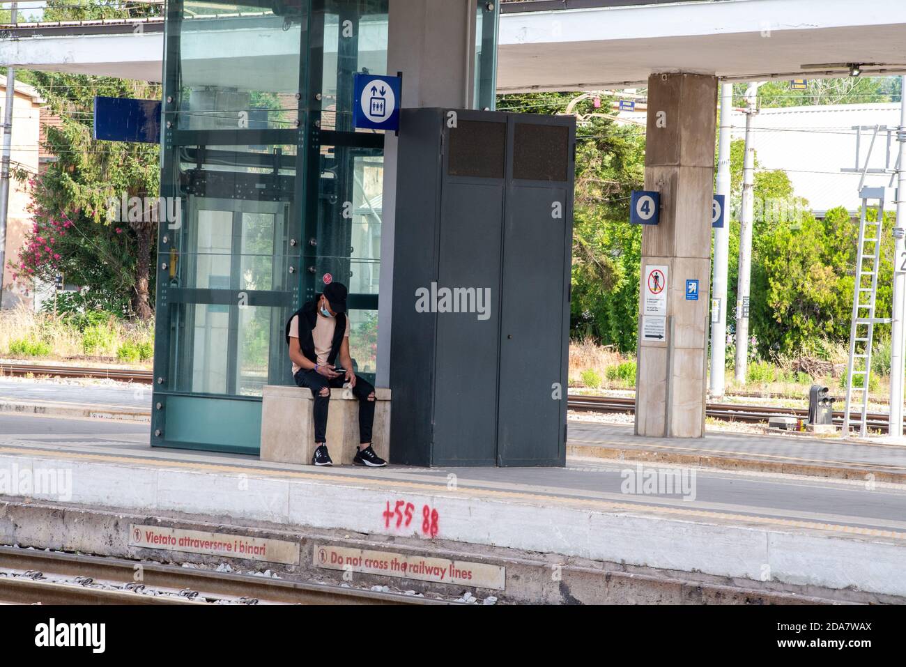 terni, italien Mai 29 2020:Junge an der Wand wartet auf den Regionalzug und trägt covid Notmaske Stockfoto